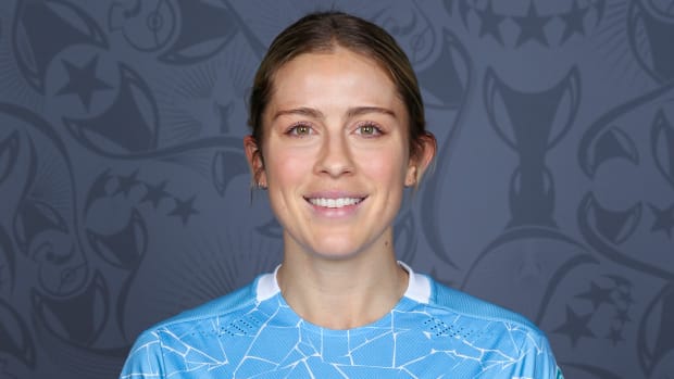 Abby Dahlkemper wears a blue soccer jersey and smiles for the camera.